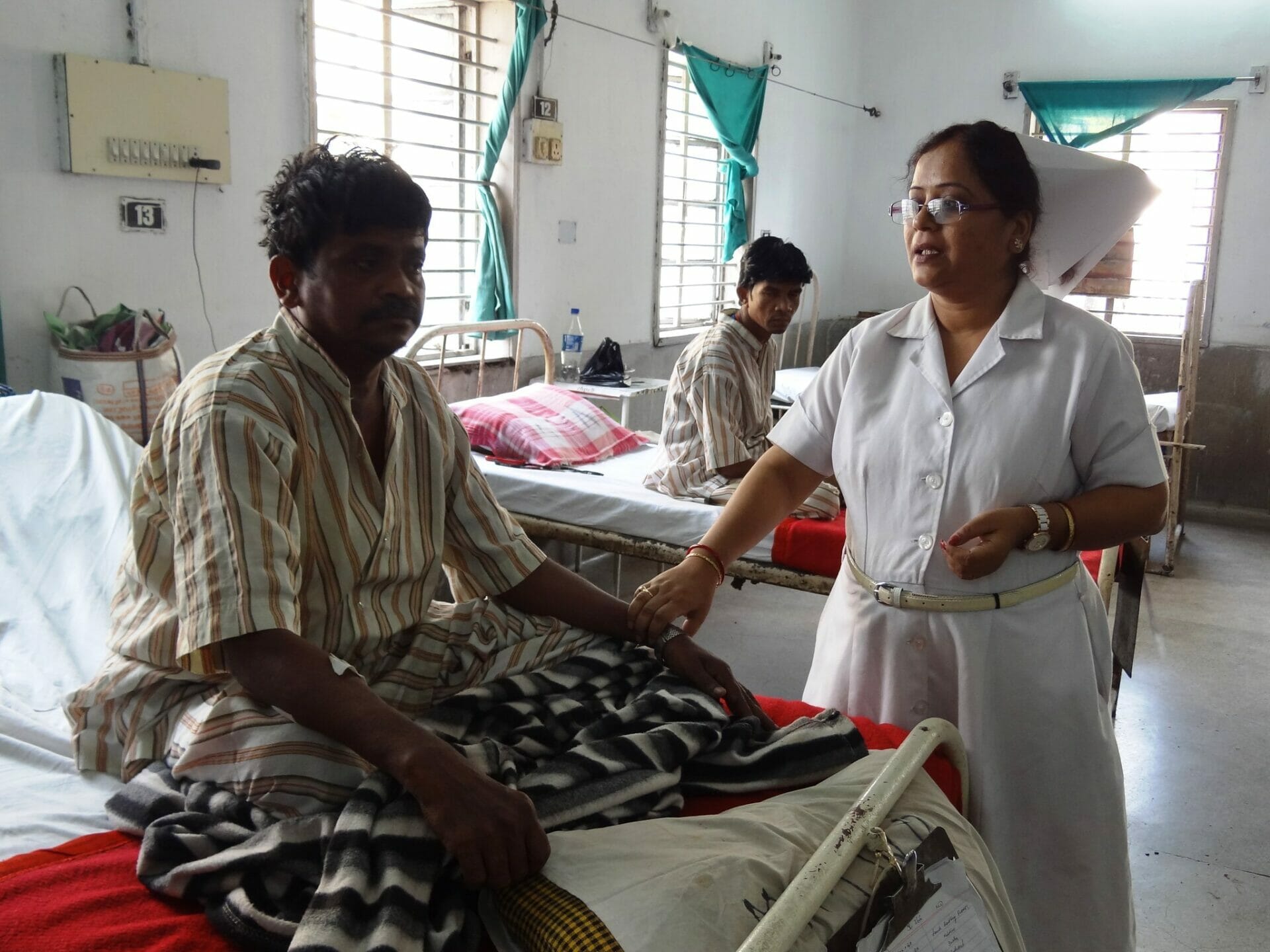 Nurse interacting with patients in a hospital ward.